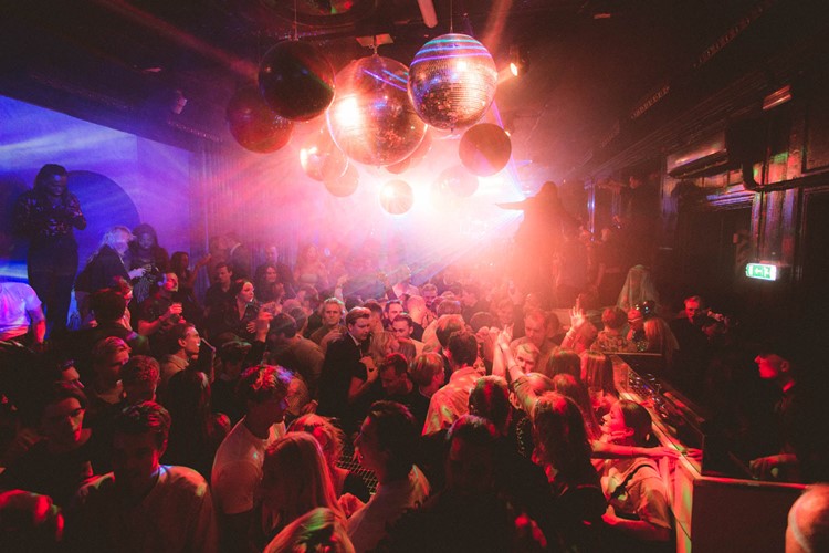 Foule dans un club baignée de lumières violettes